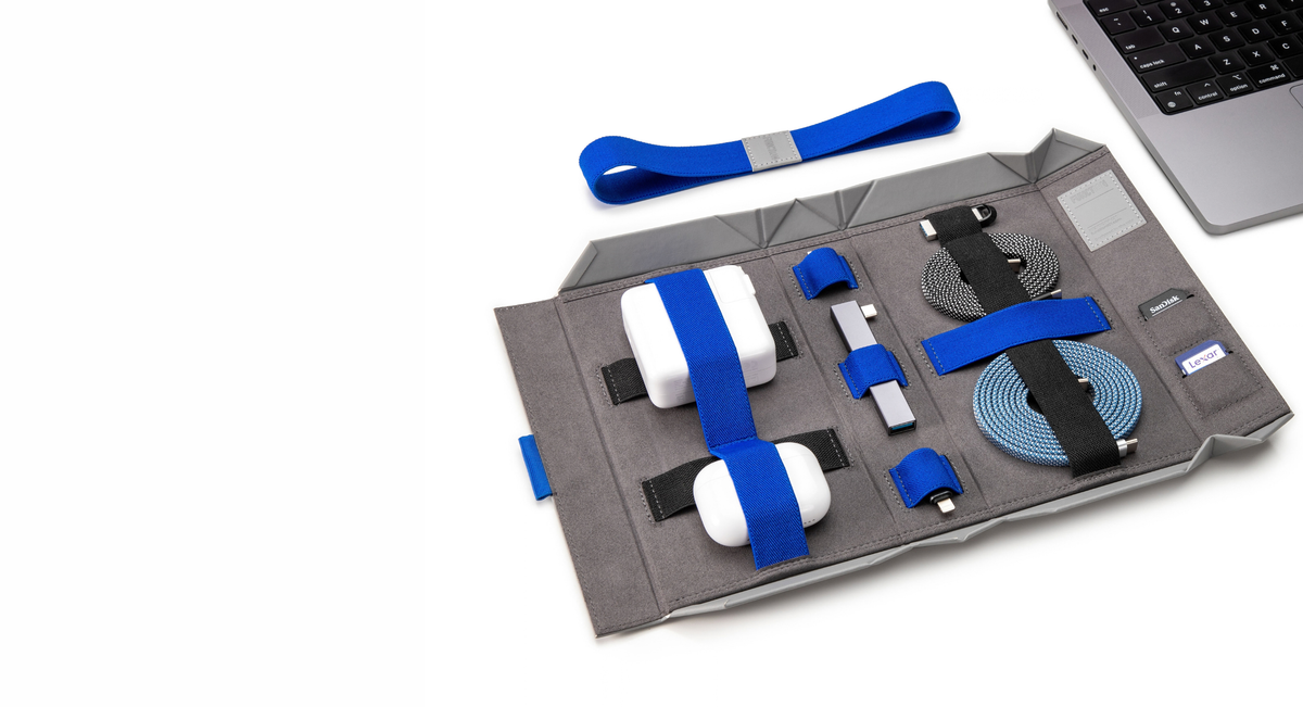 BentoPack tech organizer open beside a MacBook, holding chargers, cables and AirPods