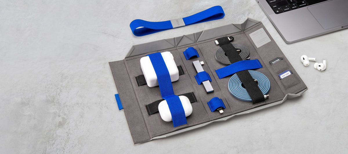 BentoPack tech organizer open beside a MacBook, holding chargers, cables and AirPods